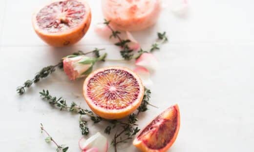 sliced blood orange fruits with white-and-pink petaled flowers beside