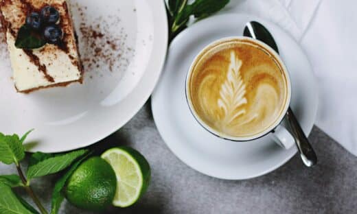 flat lay photography of coffee in teacup near plate of sliced cake